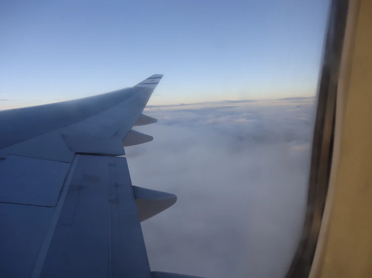 airplane wing through window and view of clouds below