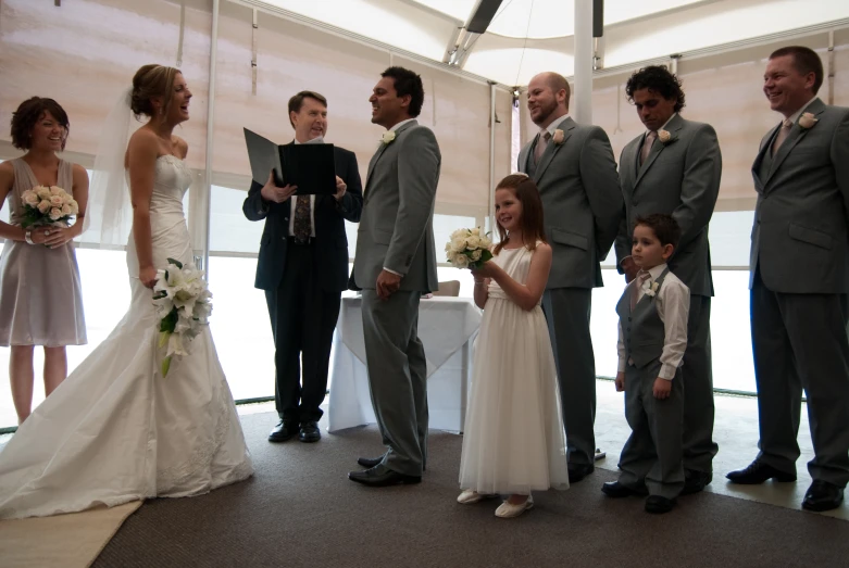 a bride and groom stand with their ring bearer during a wedding ceremony