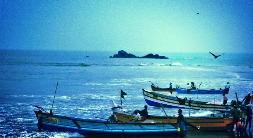 three fishing boats are pulled into the water by people