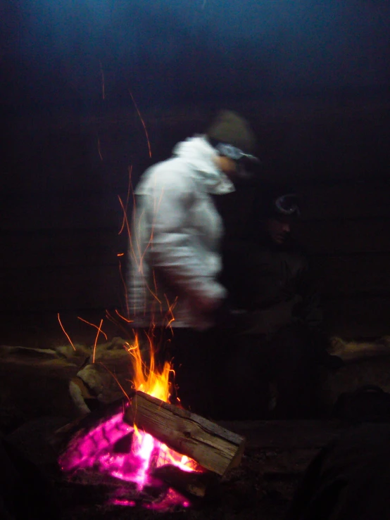 a man is standing next to a campfire at night