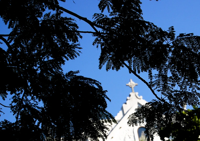 a white church with a cross in the trees