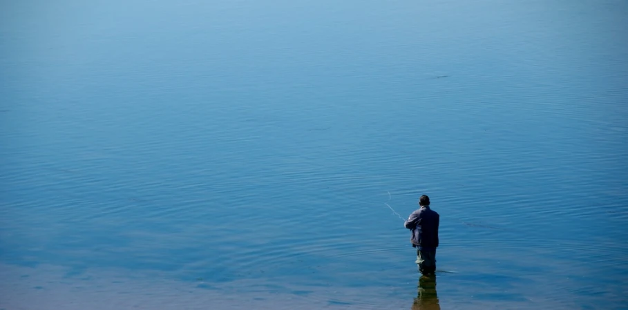 a man standing in the water and fishing