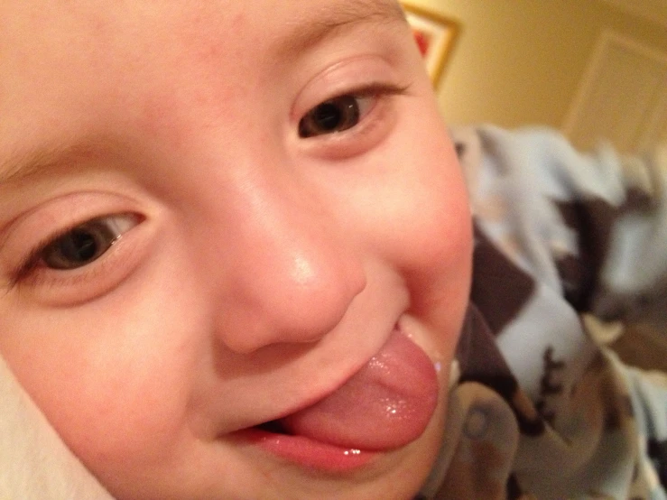 a child smiles for a picture while getting tongue rubs