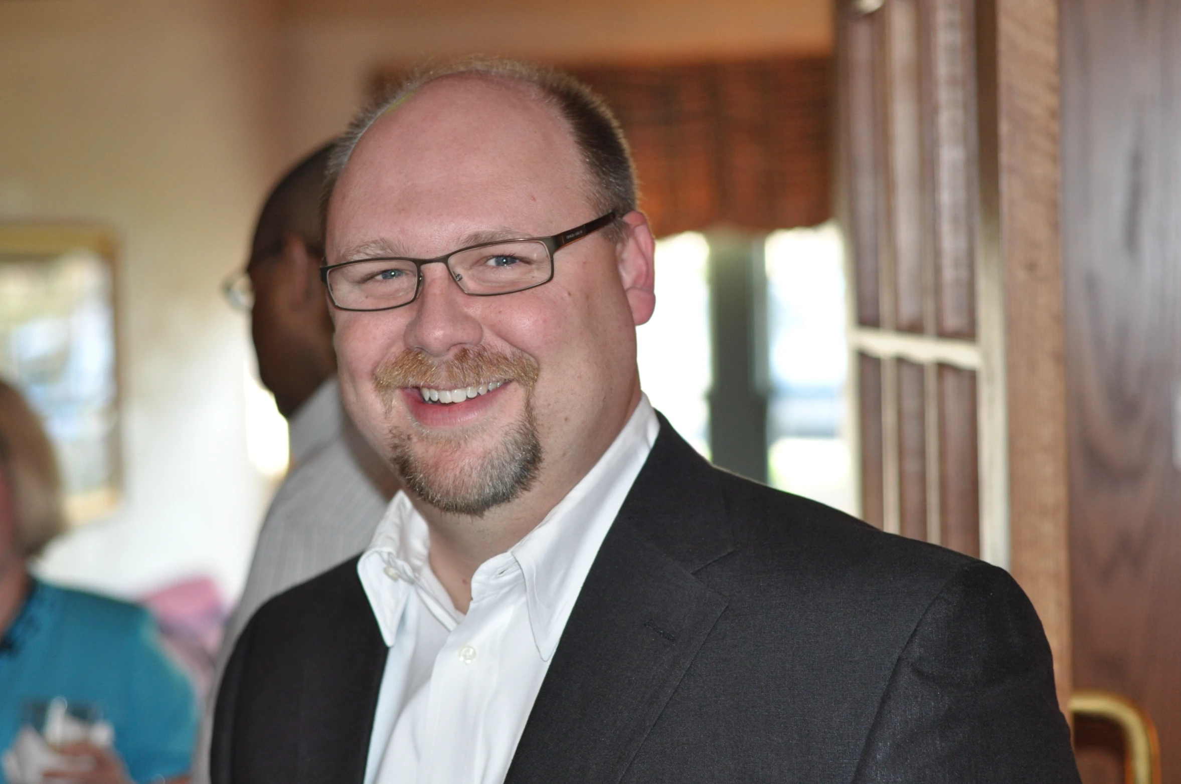 man in black and white suit and beard smiling