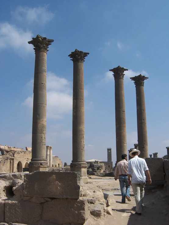 two people walk between some ruins while another watches