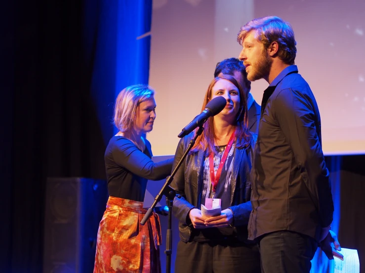 a group of people standing on stage next to a microphone