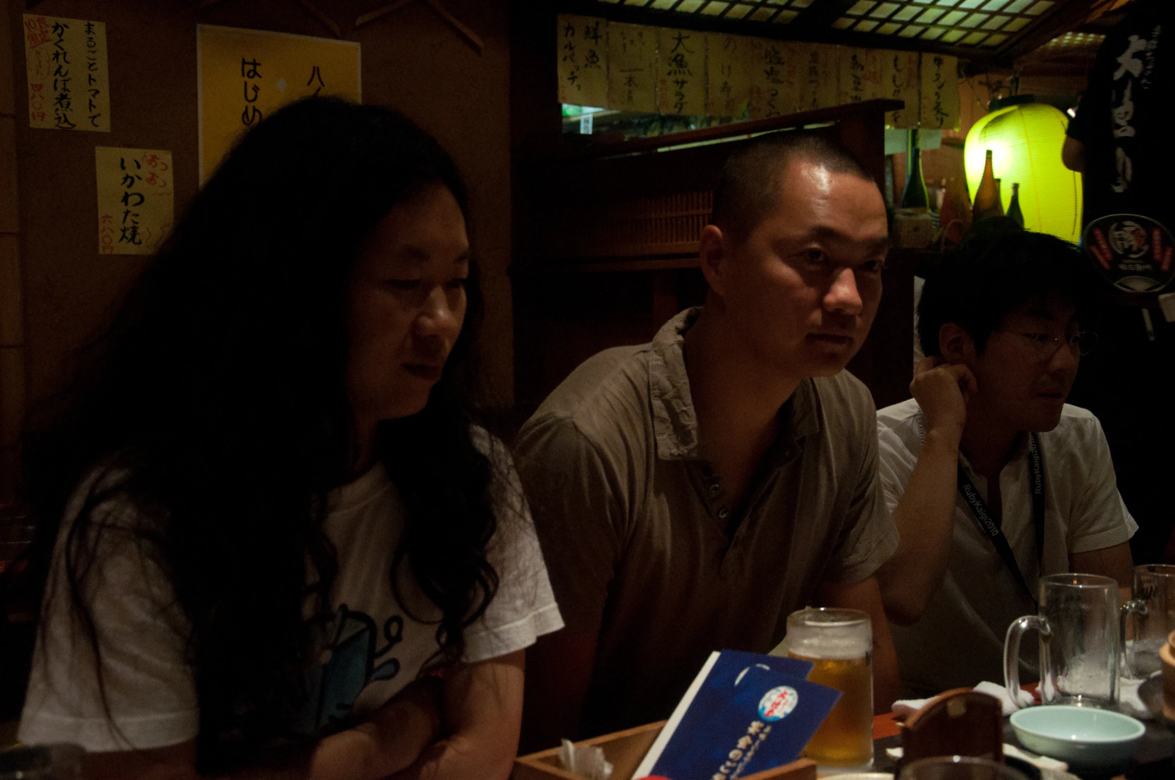 four people sitting in a restaurant and one person standing in front of the camera taking a picture