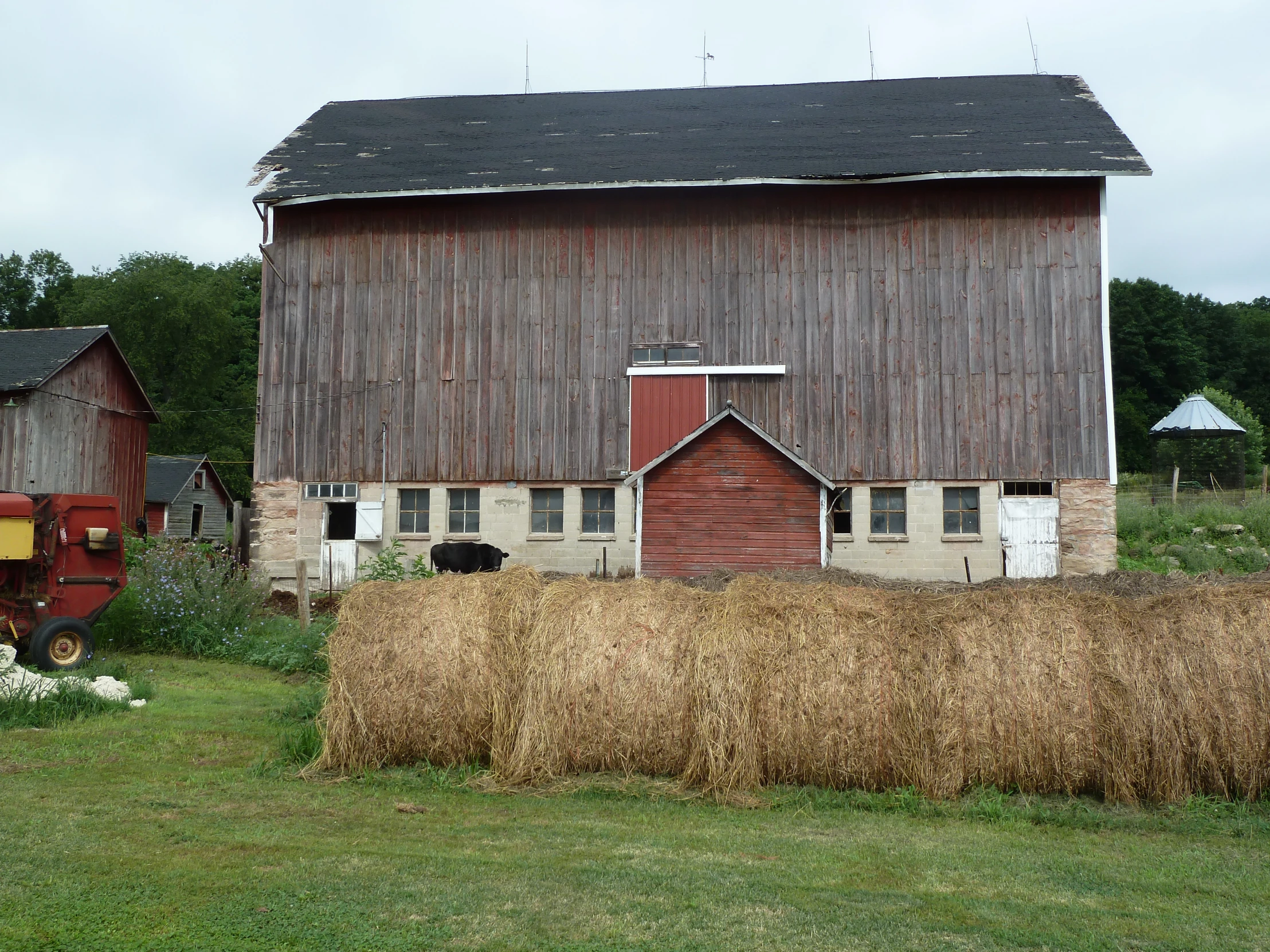 a large red barn sitting next to a pile of hay