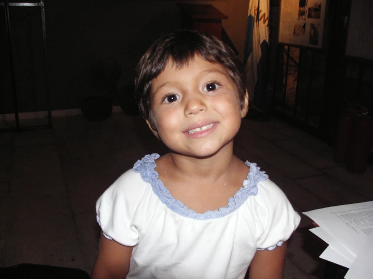 a young child in white shirt with blue collar smiling