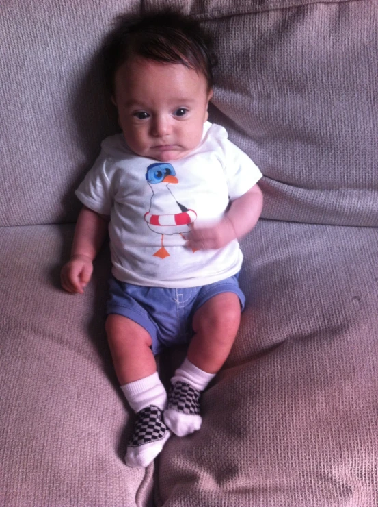 a baby laying down wearing some socks and holding a shirt