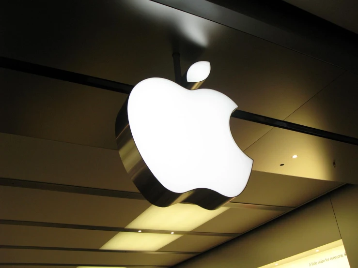 the large apple logo glows bright in a darkened space