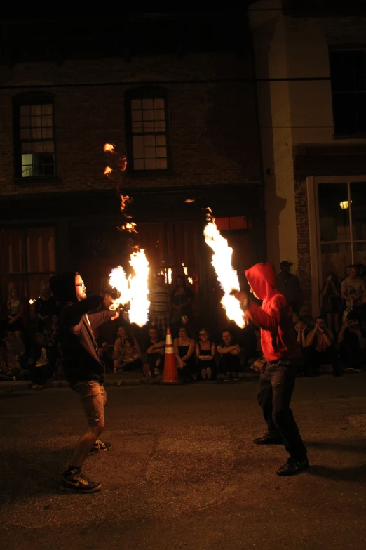 two people performing with flame in front of a crowd