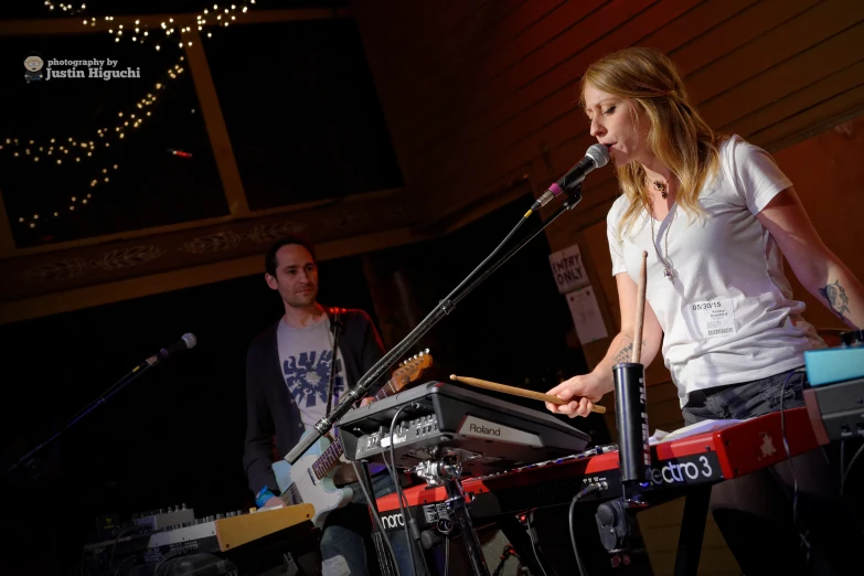 there is a woman playing a keyboard at a microphone