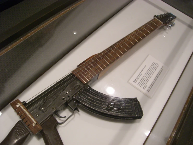an old musical instrument and an ak - 47 rifle are on display in a glass case