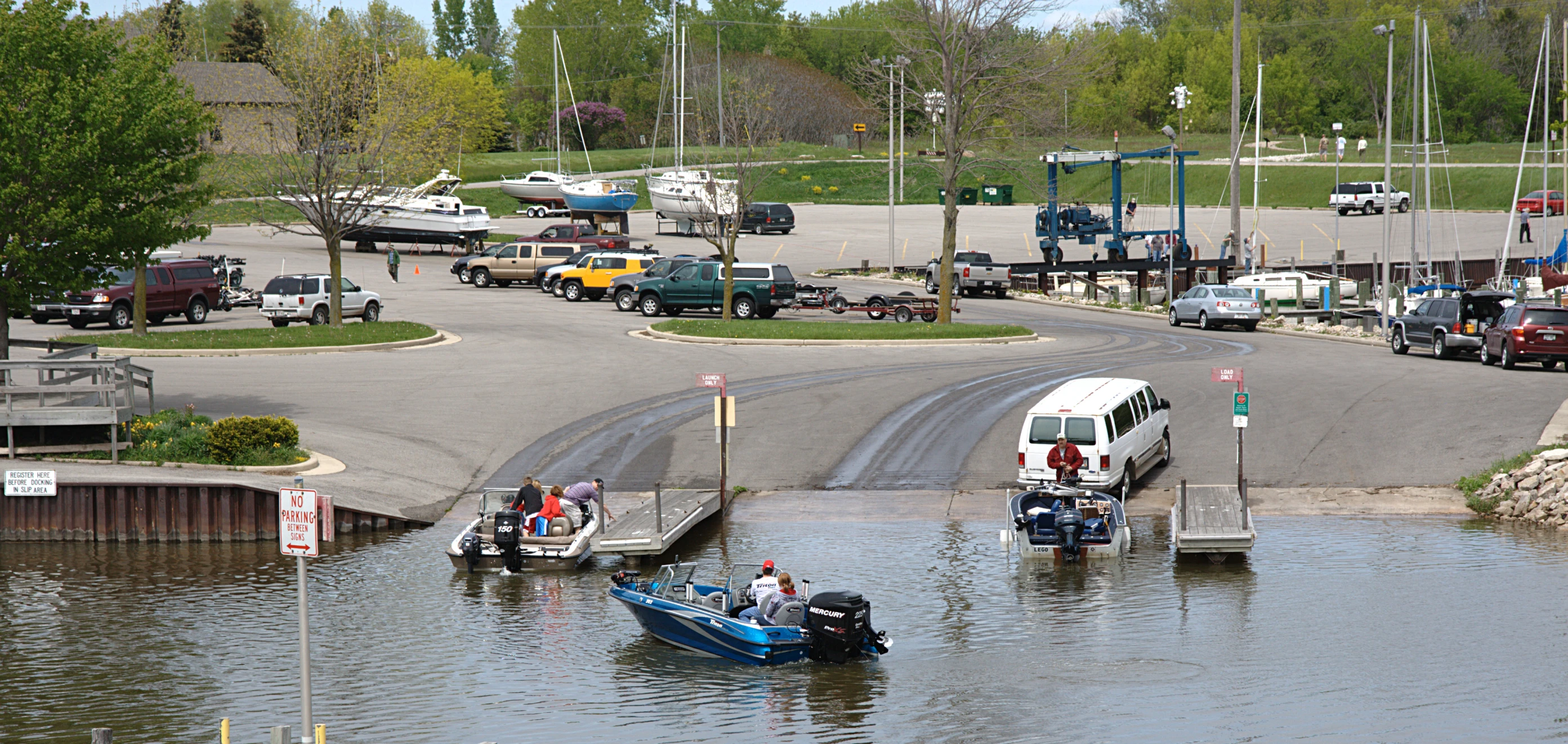 a lot of cars on the street, on which a man is standing and driving a boat