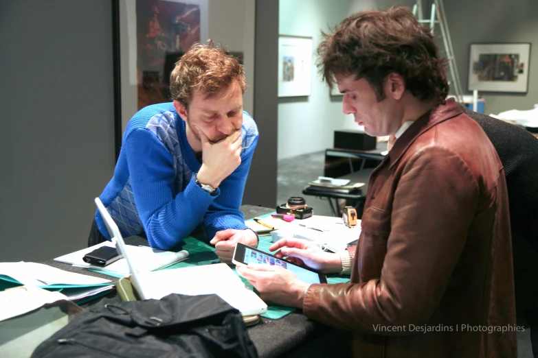 a man sitting down with a woman looking at her phone