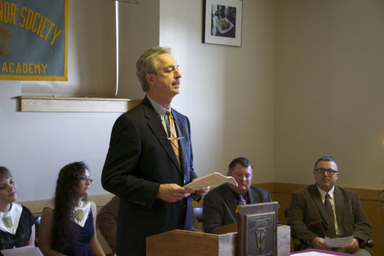 a man giving a speech at a church with other people