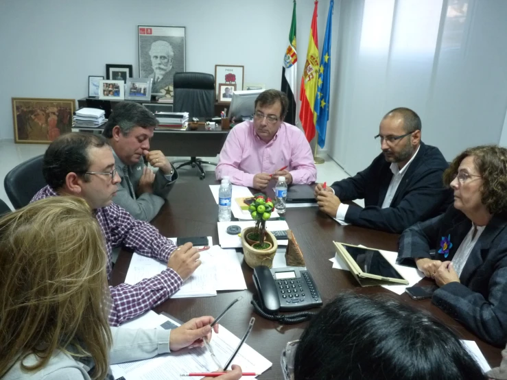 some people sitting around a large table with papers and computers