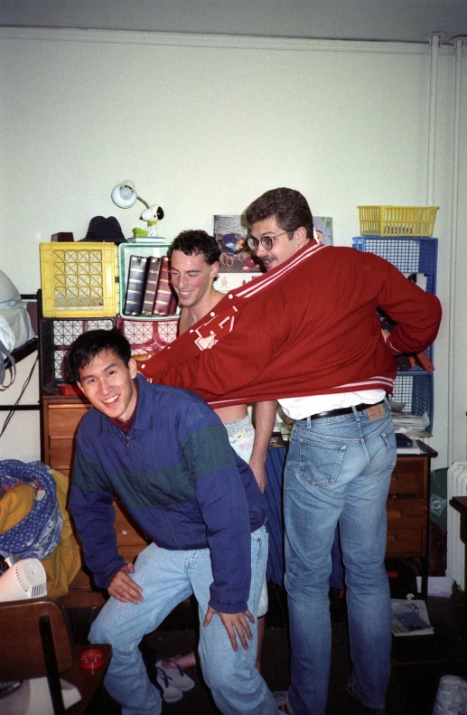 three men standing in a dorm room posing for the camera