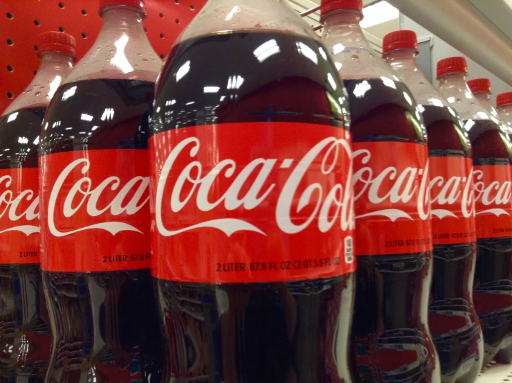 several bottles of coca - cola sitting on a shelf