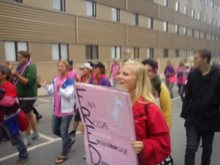 young women in pink hold signs and cheer during the parade