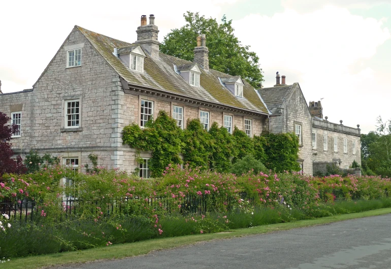 a building with green bushes on it and flower around the front