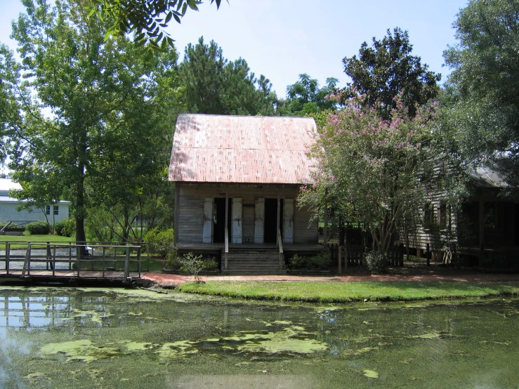 a house sits on a pond with lily pads around it