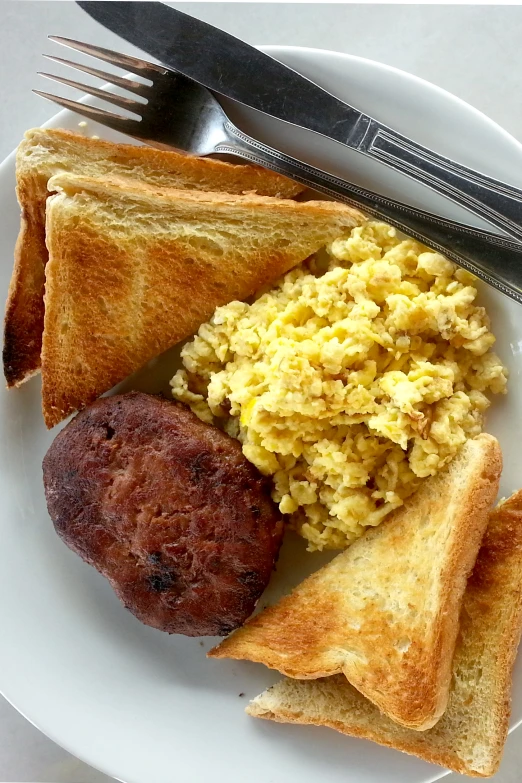 a plate containing fried egg, toast and sausage on bread