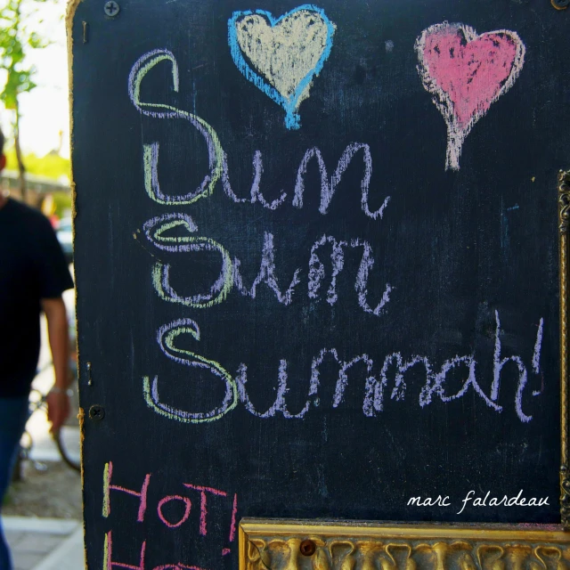 two chalk writing words on a black board next to a couple of people