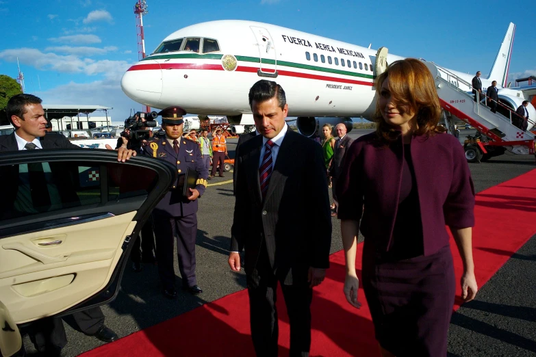 the president of chile walks beside a woman who is next to an airplane
