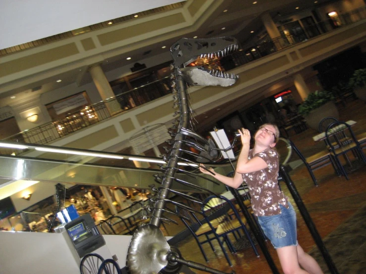 woman walking with a large metal dinosaur model