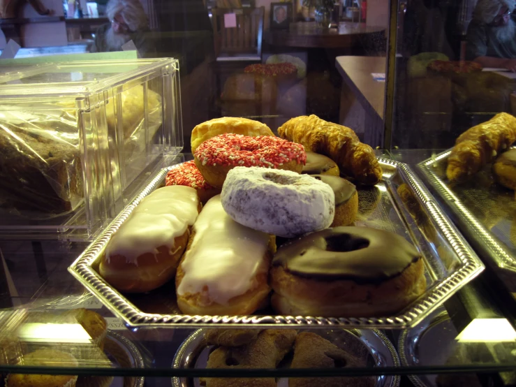 assorted doughnuts are displayed behind a glass case