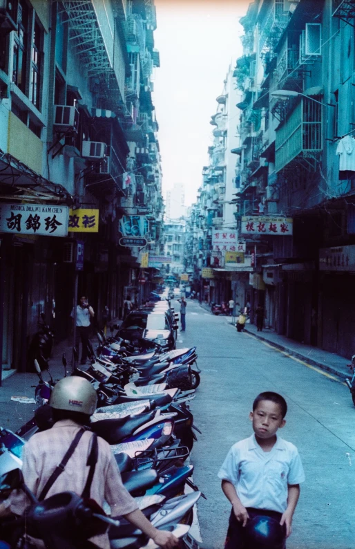 two boys in the street looking back at a large row of parked scooters