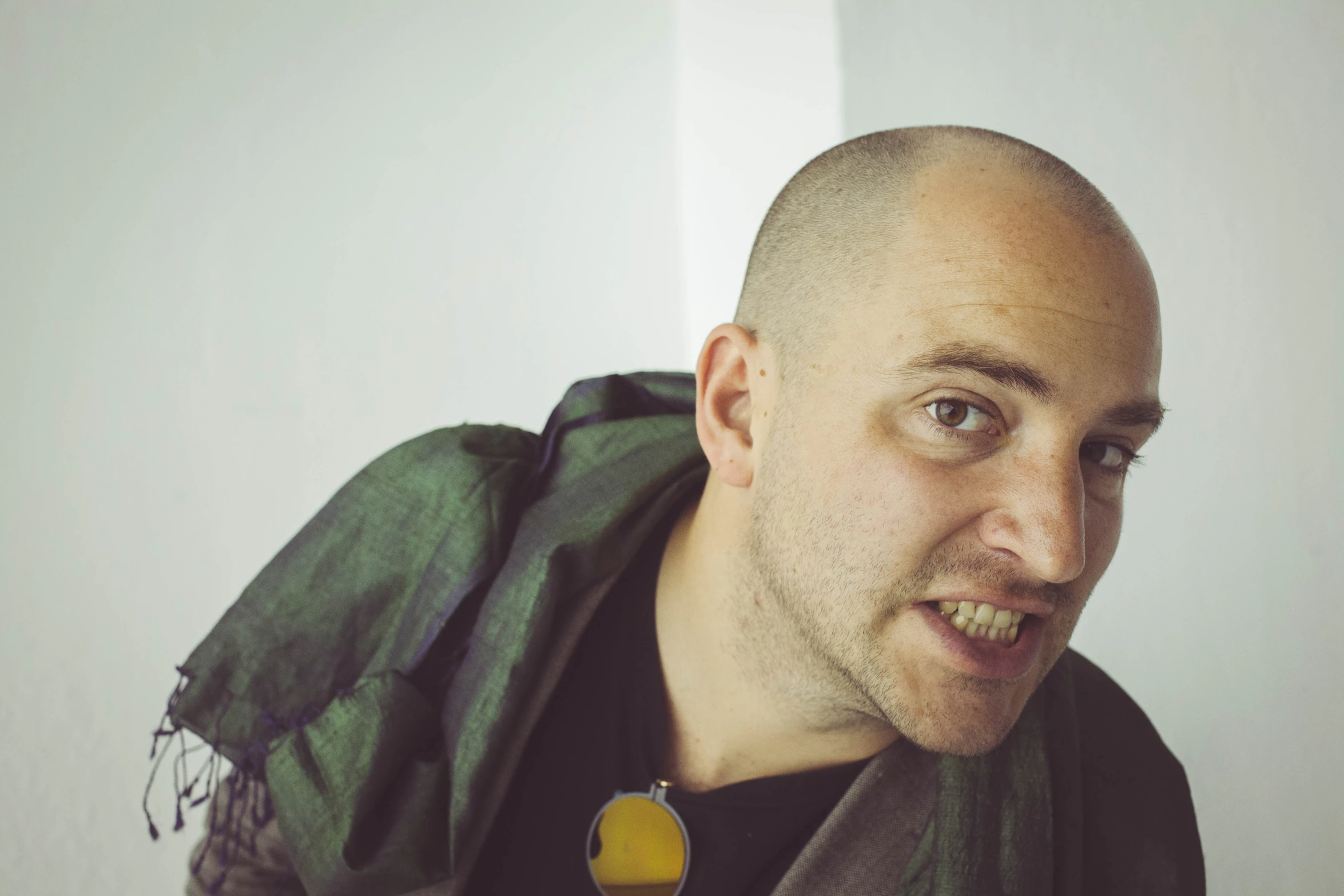 a bald man wearing a scarves and scarf looks into the camera