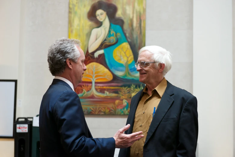 a couple of men standing next to each other in front of a painting