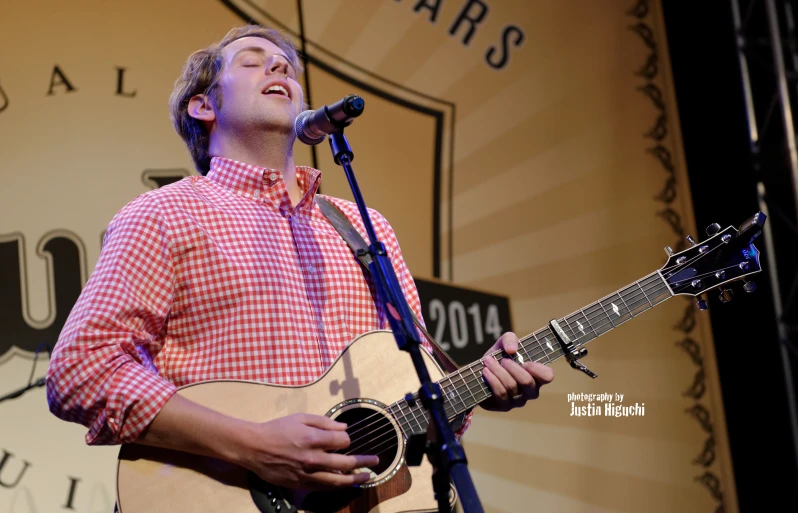 a man with an acoustic guitar in front of a microphone