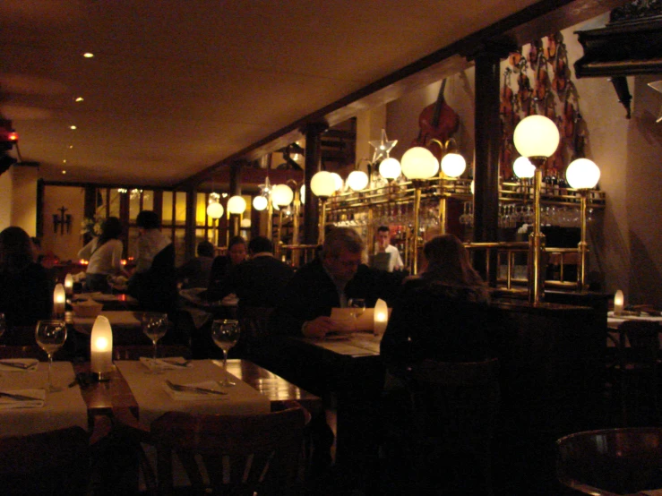 a crowded restaurant with white lights on the wall and candles