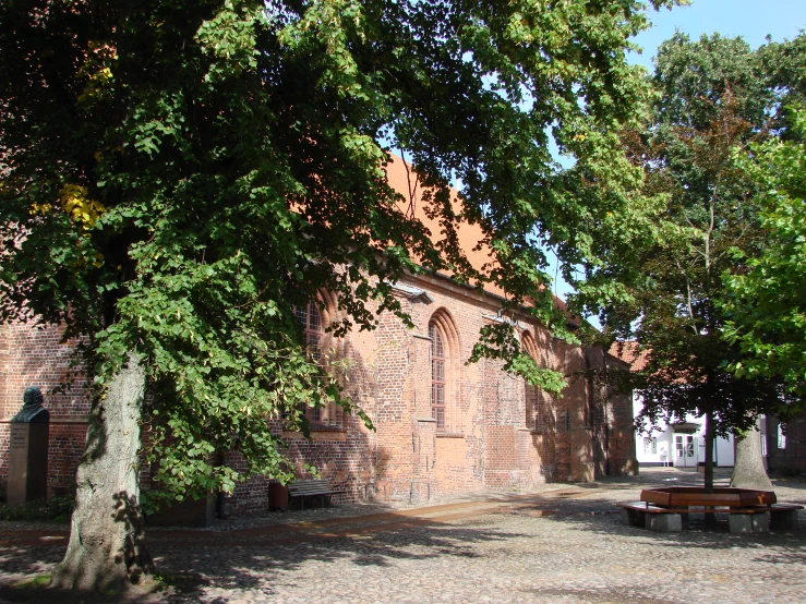 a brick building with benches underneath tree's in front of it