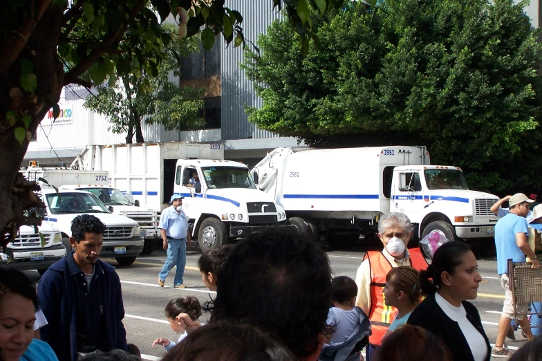 a crowd of people walking around white trucks