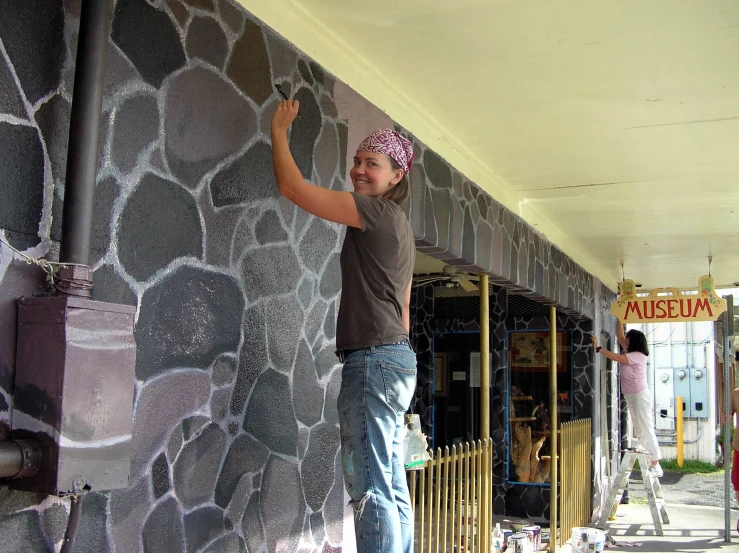 a woman is painting the outside of a store