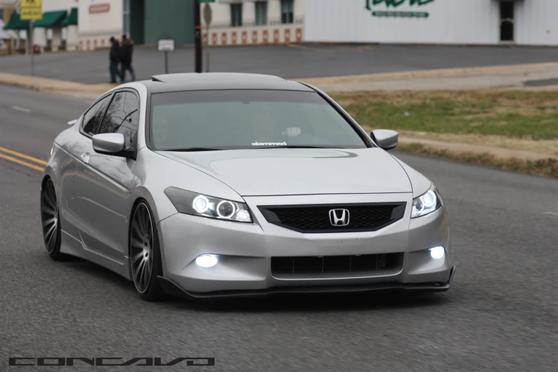 a silver car with headlights on a street