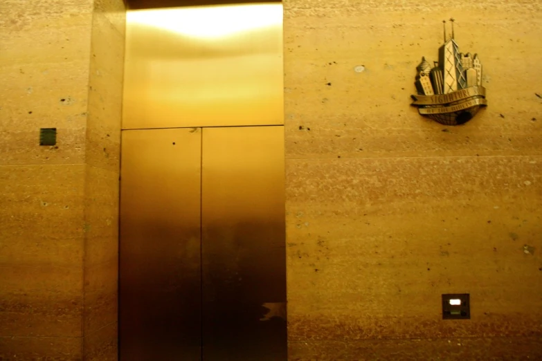 a golden door and a small sign are on a wall