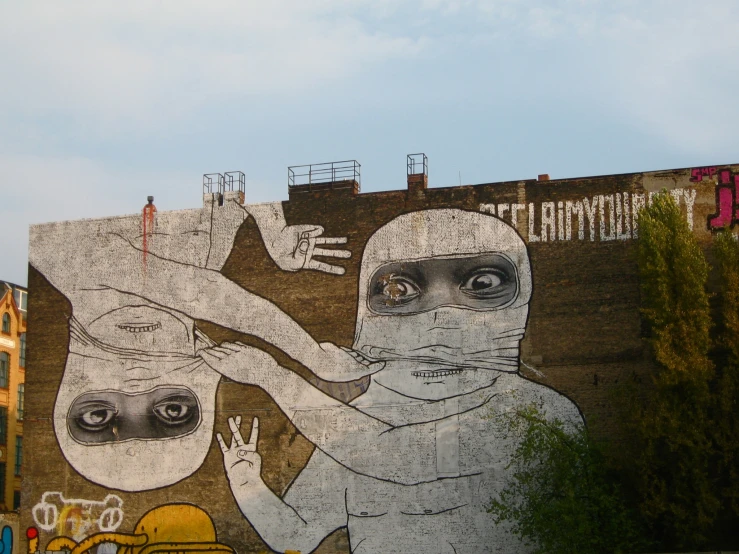 a mural of two people in masks is seen against a brick wall