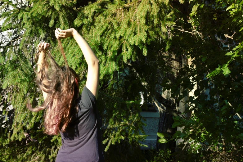 a girl holding a remote controller in front of a green tree