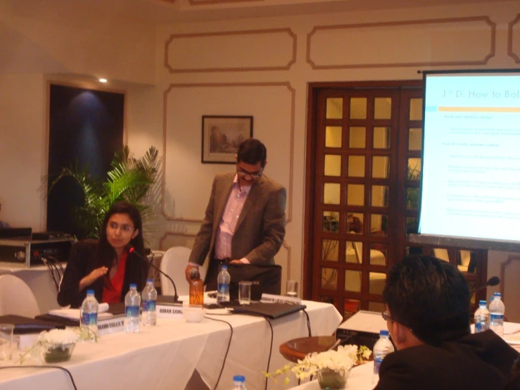 man presenting during a seminar on laptop computer and projector screen