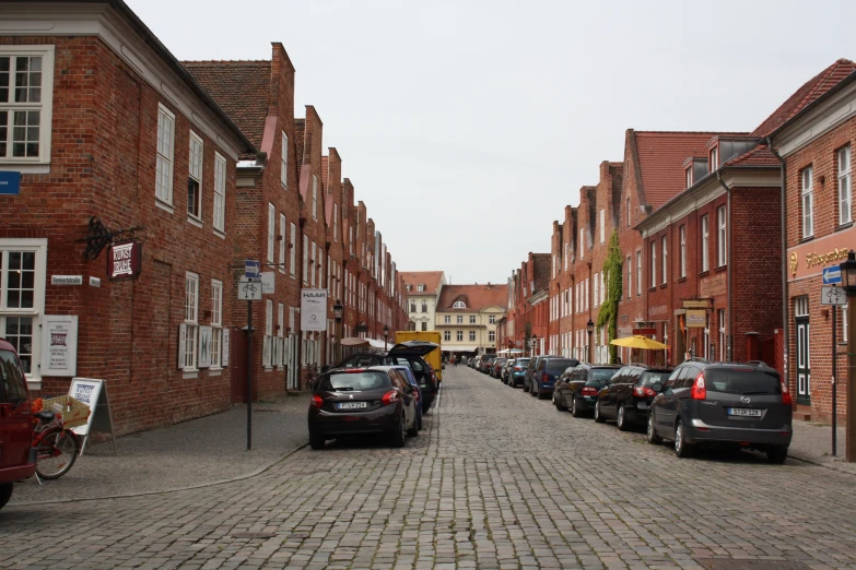parked cars on a street lined with small brick buildings