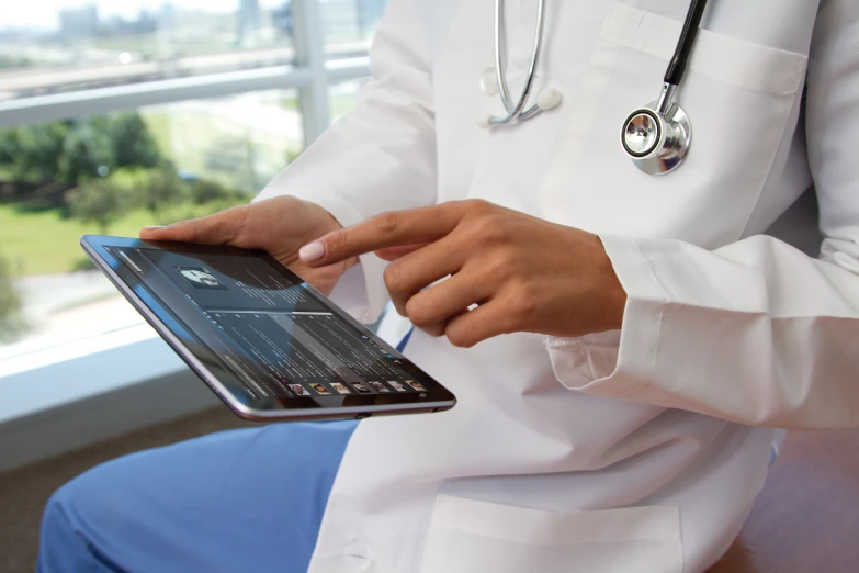 a doctor wearing white holds an open laptop computer