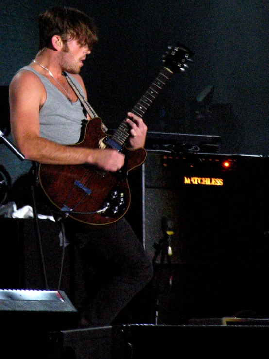 a male in a grey shirt playing a guitar