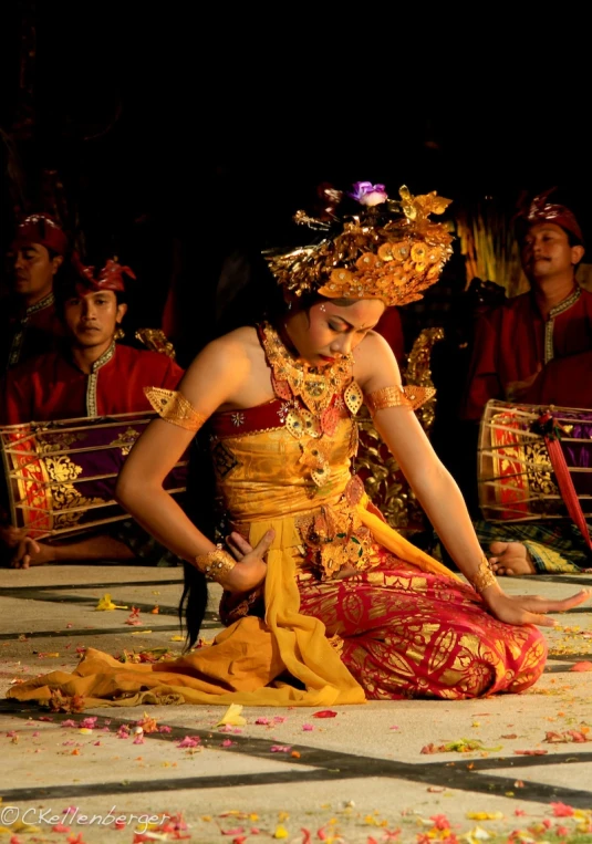 a women sitting down in a room while dressed in colorful dress