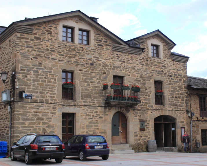 two vehicles parked outside an old stone building